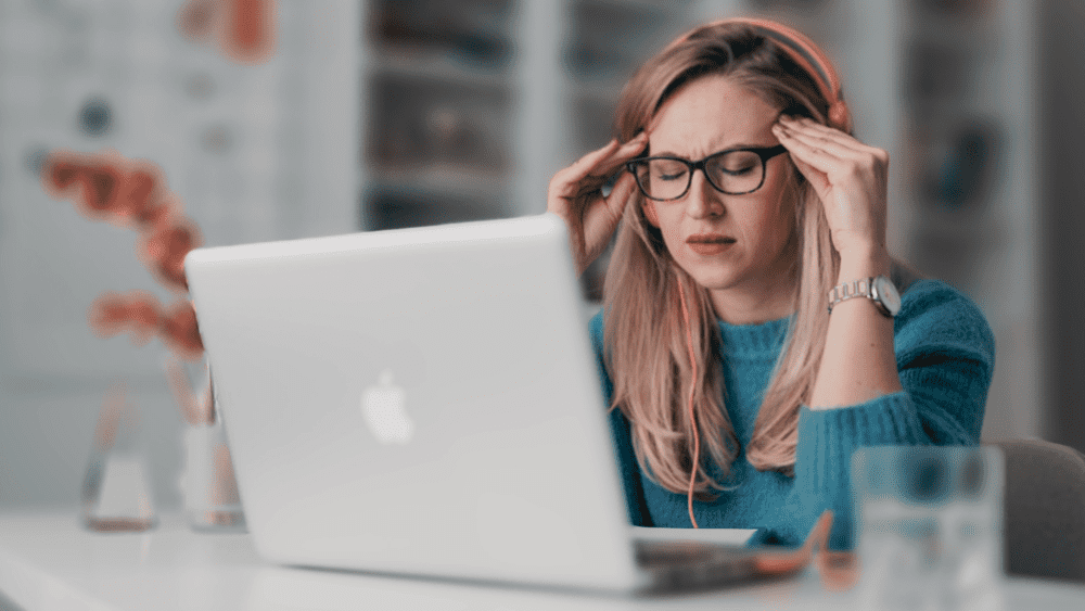 A stressed looking female professional, sitting in front of her laptop.