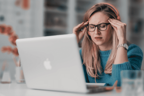 A stressed looking female professional, sitting in front of her laptop.