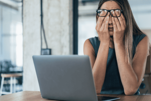 A woman feeling busy and overwhelmed at her laptop.